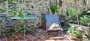 Relax in a charming outdoor seating area surrounded by lush greenery and a stone wall.