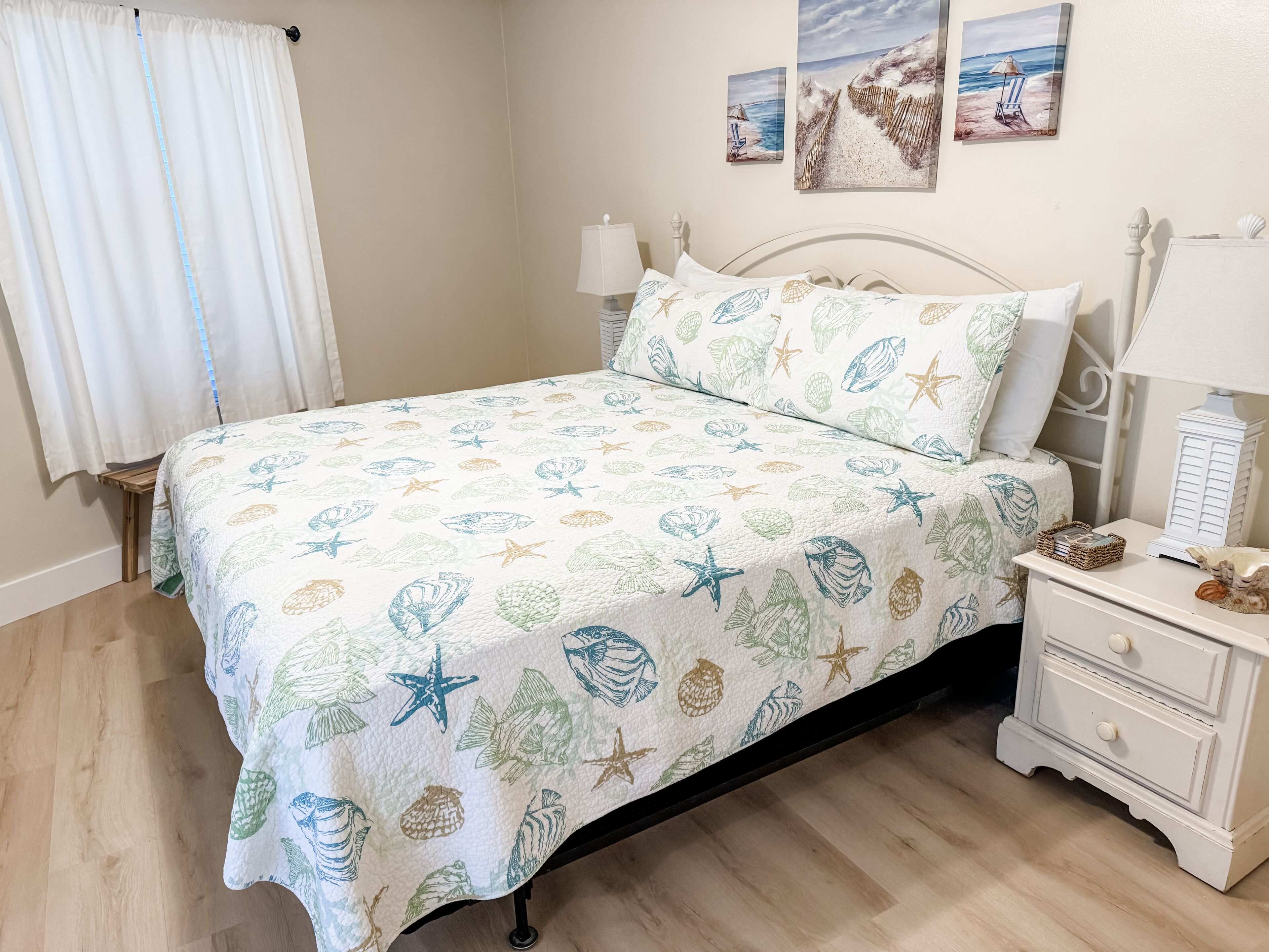A bedroom with a bed, a nightstand, a lamp, and a wall with two paintings.