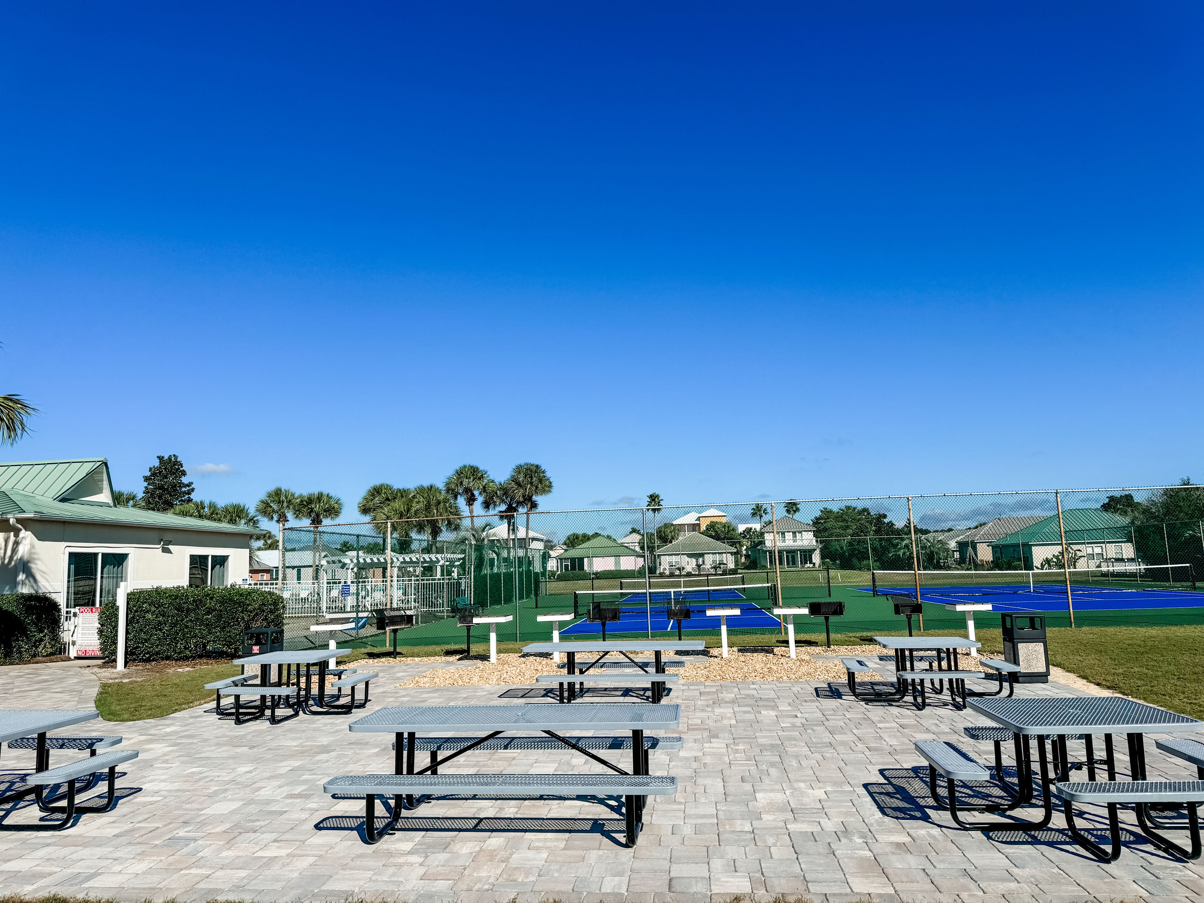 Un parc équipé de tables de pique-nique, d’un court de tennis et d’un bâtiment doté d’un toit végétalisé.