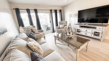 Een woonkamer met een bank, fauteuils, een salontafel, een televisie en een kast.