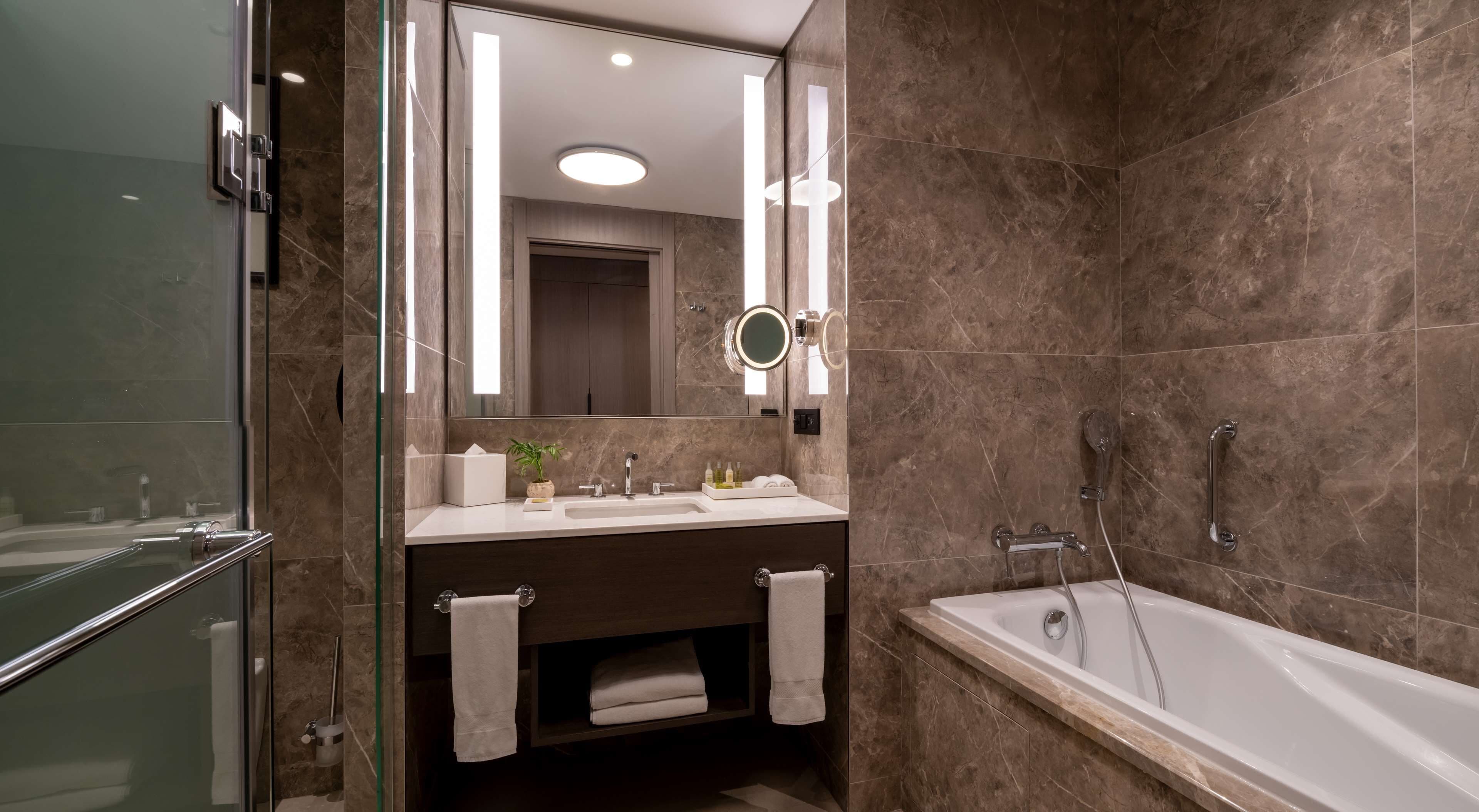 A modern bathroom with a glass shower enclosure, a bathtub, and a vanity with a mirror.