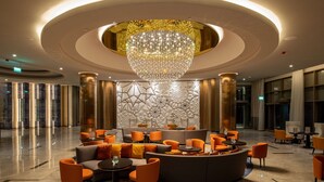 A spacious lobby with a large chandelier, modern seating arrangements, and a decorative wall with geometric patterns.