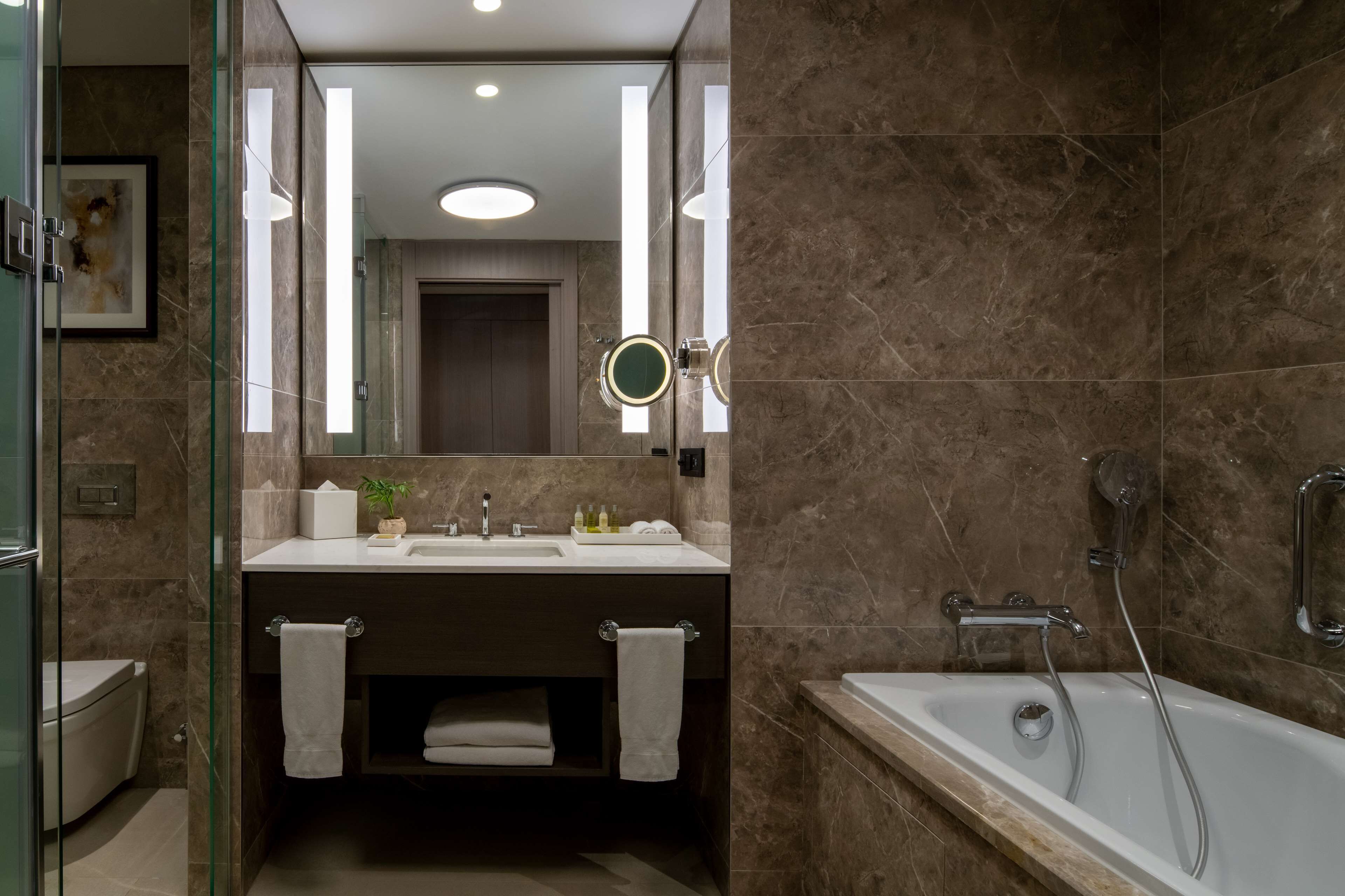 A modern bathroom with a glass-enclosed shower, a double sink vanity, and a bathtub.