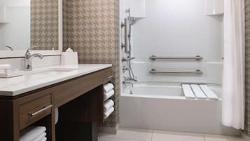 A modern bathroom with two sinks, a mirror, a shower, and a bathtub.