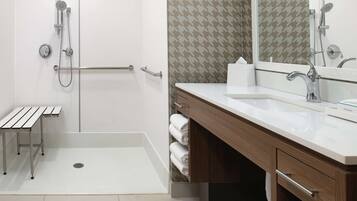 Un bagno moderno con doccia a filo pavimento, un lavabo e uno specchio.