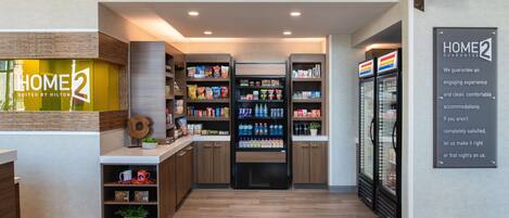 Een hotellobby met een receptiebalie, automaten en een bord met daarop 'HOME 2 guarantee'.