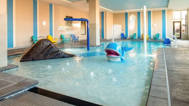 An indoor swimming pool with a water slide, lounge chairs, and a sign indicating no lifeguard on duty. - Home2 Suites By Hilton Boise Downtown (Boise)
