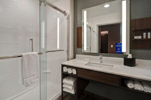 Un baño moderno con cabina de ducha de vidrio, un lavamanos blanco y un espejo grande.