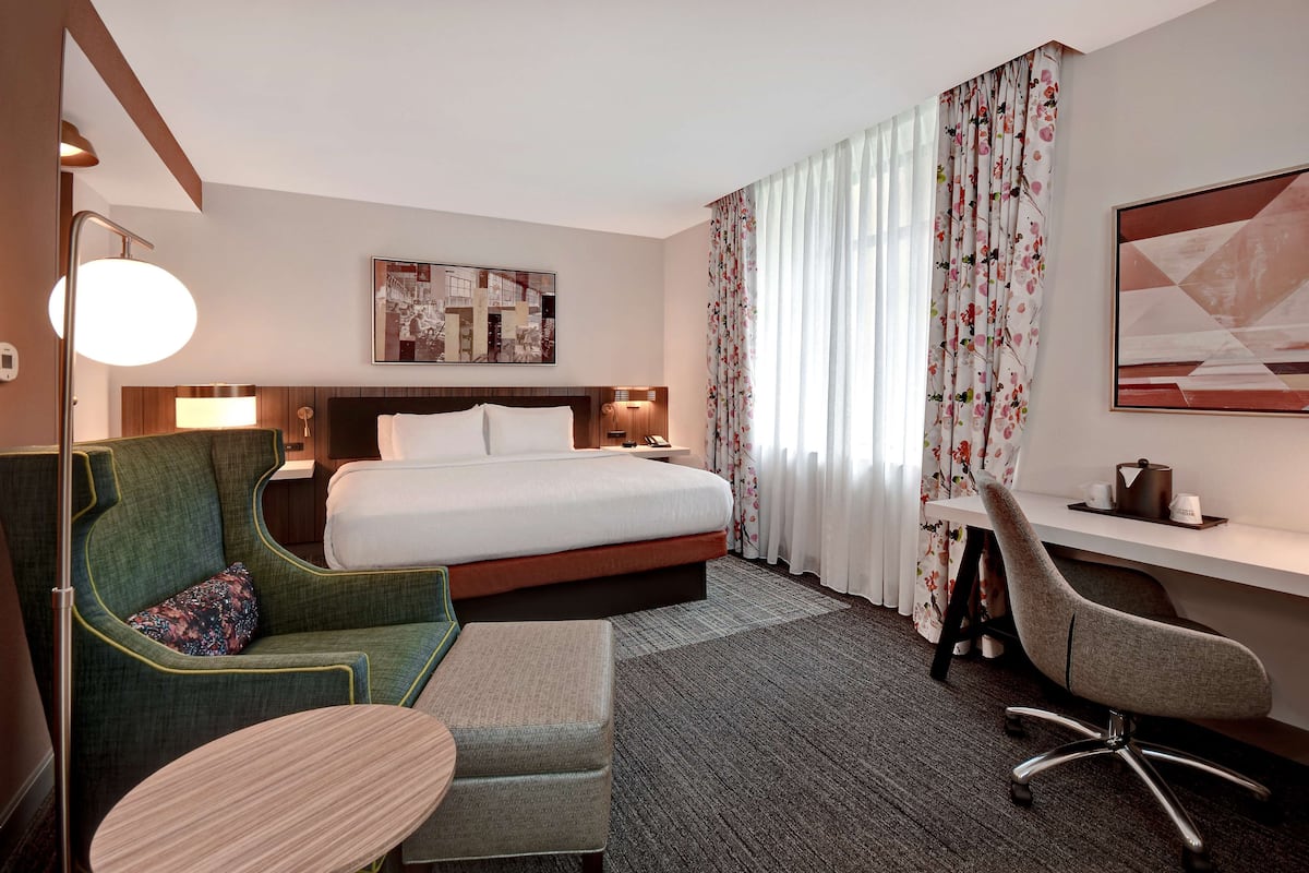 A hotel room with a bed, a desk, a chair, a sofa, and a small table.