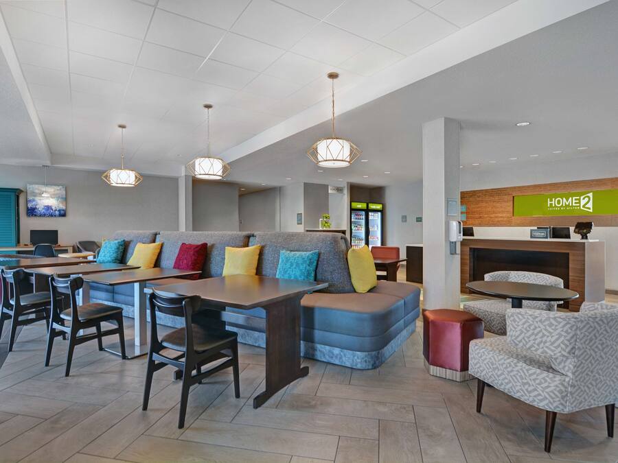 A modern hotel lobby with a seating area, a reception desk, and a vending machine.