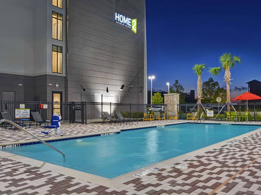 A hotel pool area with a checkered tile floor, lounge chairs, and a sign indicating no diving.
