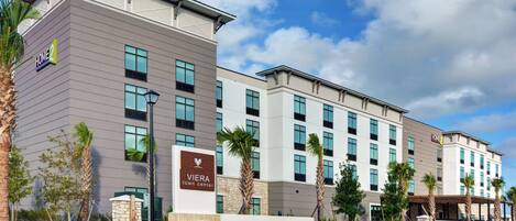 A modern hotel with a sign reading "Viera Town Center" and "Home2" on the facade.