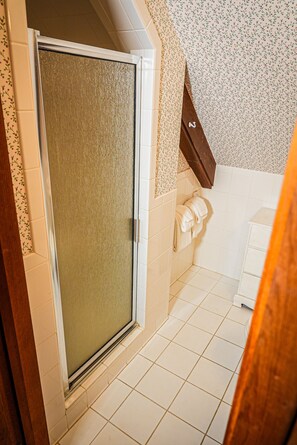 Bathroom features a shower area with a frosted glass door, white tiles, and a towel rack.