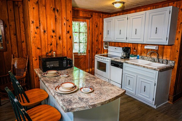 Compact kitchen with cabinetry, stove, microwave, and dishwasher, offering ample workspace and a convenient sink and coffee maker.