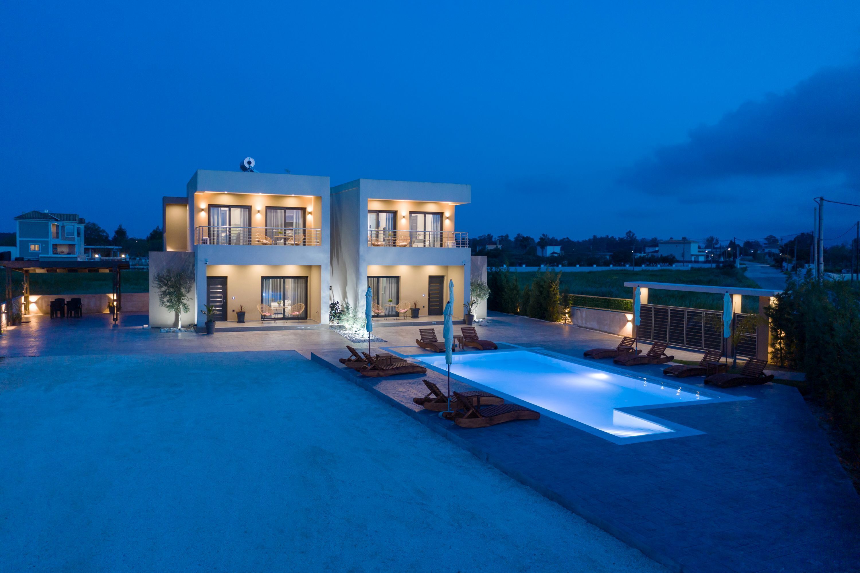 A modern two-story building with a swimming pool and outdoor seating.