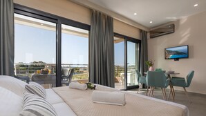 A hotel room with a large bed, a balcony with a table and chairs, and a TV mounted on the wall. - La Casa De Zante (Zakynthos)