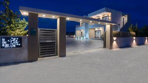 A modern two-story building with a gated entrance, illuminated by overhead lights. - La Casa De Zante (Zakynthos)