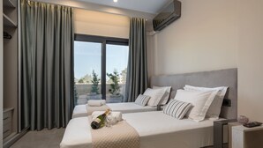 A modern hotel room with two beds, a large window with curtains, a minibar, and a view of the outdoors. - La Casa De Zante (Zakynthos)