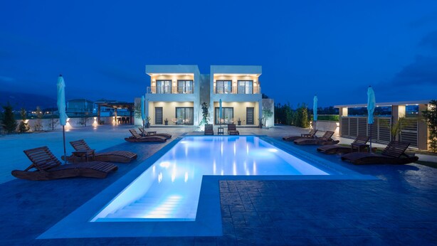 A modern hotel with a swimming pool, sun loungers, and a well-lit entrance. - La Casa De Zante (Zakynthos)