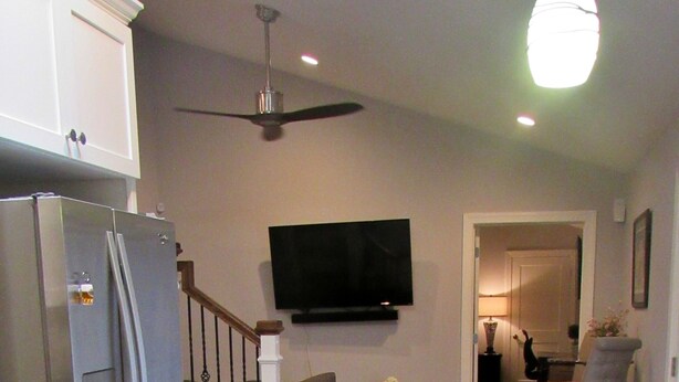 Una cocina moderna con refrigerador empotrado, una zona de comedor con mesa y sillas, un televisor de pantalla plana en la pared y un ventilador de techo.