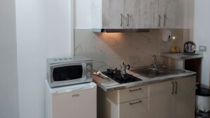A compact kitchen with white cabinets, a built-in microwave, and a stove. - Studio in villa with amazing sea view (Vlorë)