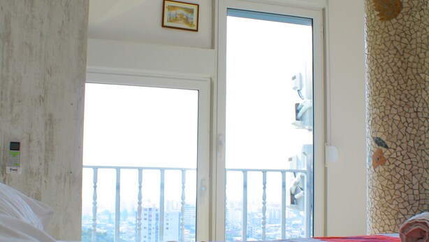 A hotel room with a bed, a door leading to a balcony, and a view of the cityscape. - Studio in villa with amazing sea view (Vlorë)