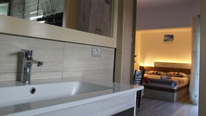 A modern bathroom with a white sink, a mirror, and a ceiling fan. - Studio in villa with amazing sea view (Vlorë)