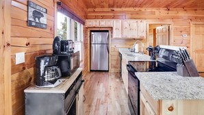 Cocina de cabaña de madera con un refrigerador de acero inoxidable, una cafetera y un bloque de cuchillos.