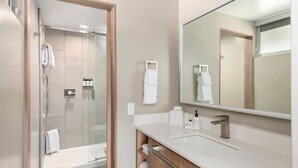 A modern bathroom with a glass shower enclosure, a large mirror, and a white countertop. - Uptown King Dog Friendly w/ Private Patio  and  Mountain View @ The Matterhorn Inn (Sedona)
