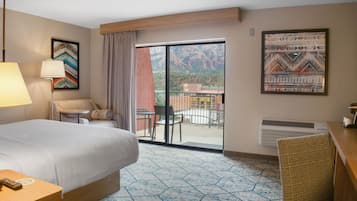 Une chambre d’hôtel équipée d’un lit, d’un bureau, d’une chaise, d’une table, d’une lampe, d’une fenêtre et offrant une vue sur les montagnes.