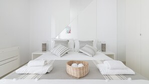 Une chambre à coucher au style minimaliste, comprenant un lit, deux tables de chevet, une lampe fixée au mur et un objet décoratif.