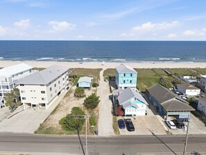 Ein Küstenwohngebiet mit Häusern direkt am Strand, einer Straße und freiem Blick auf den Ozean.