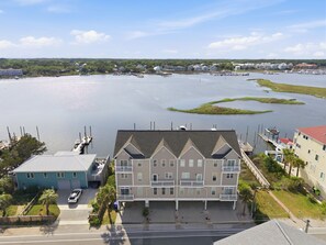 A multi-story building with a flat roof and a balcony, adjacent to a marina with boats docked.