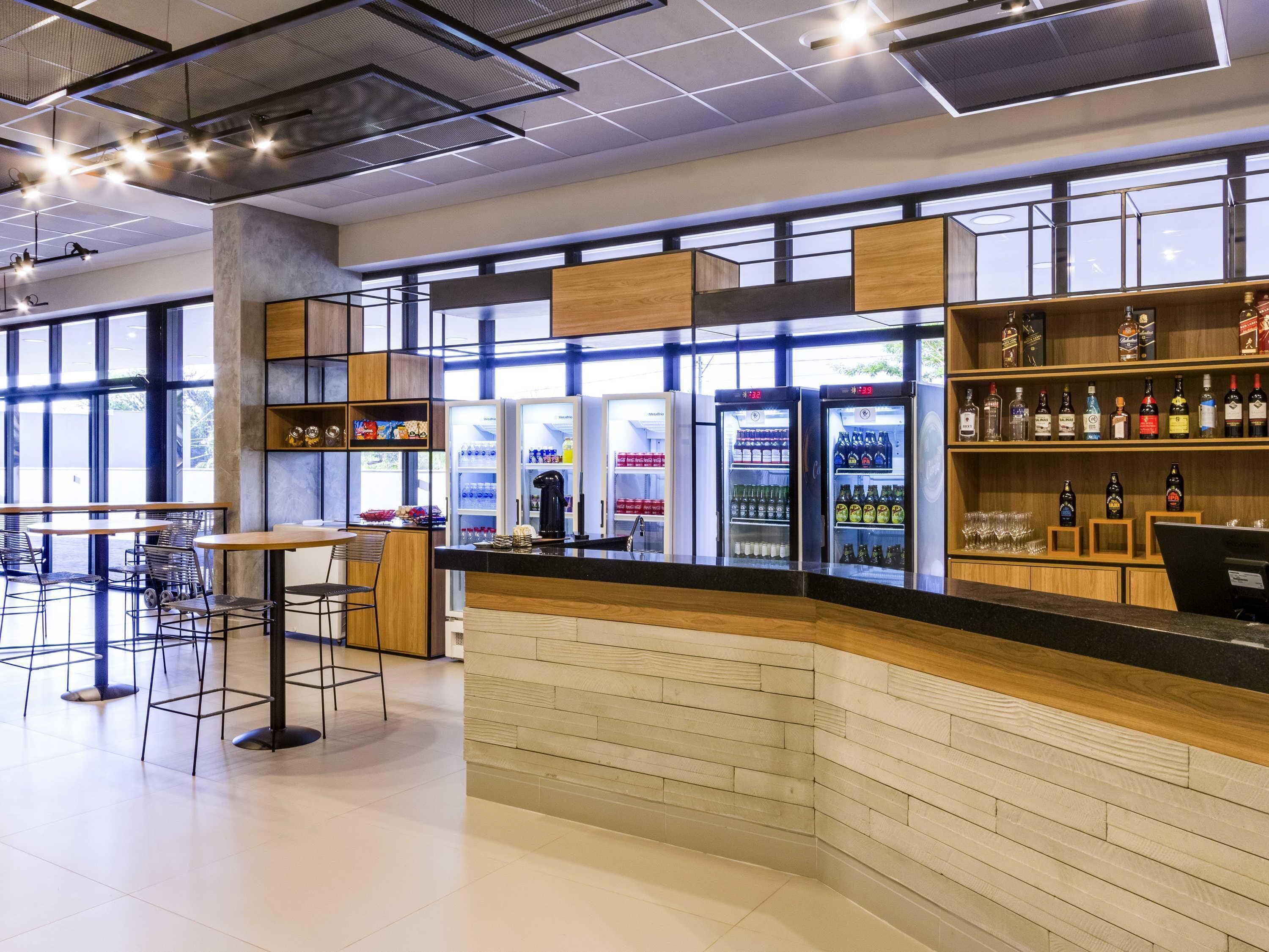 A modern bar area with seating, a counter, and beverage dispensers.