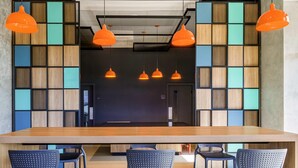A modern meeting room with a long table, six chairs, and three orange pendant lights. - Ibis Ribeirao Preto Vila do Golf Hotel (Ribeirão Preto)