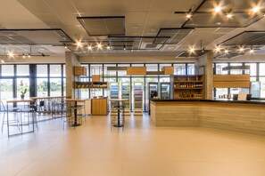 Un cafè ampli amb sostres alts, grans finestres i diverses opcions de seients, com ara taules i cadires.