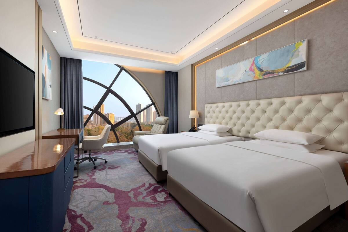 A hotel room with a large bed, a desk, and a TV.