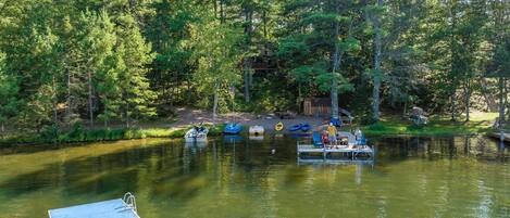 A calm lake surrounded by dense forest, with several boats docked on a wooden pier.