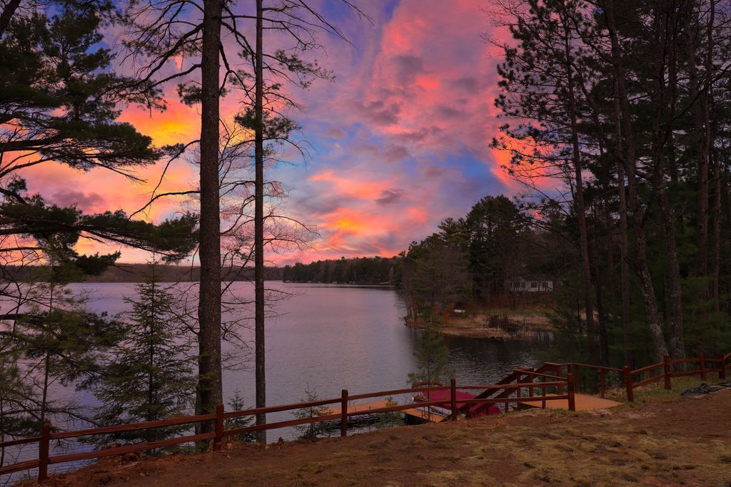 A lakeside view with a wooden deck and a wooden fence.