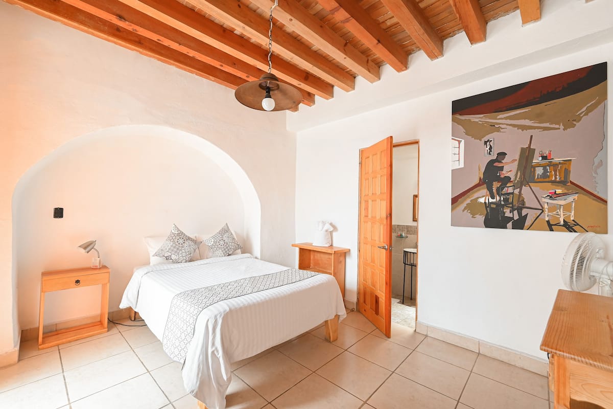 Une chambre à coucher avec un lit, une table de chevet, une lampe et un tableau au mur.