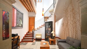 A spacious living area with a staircase, a sofa, a coffee table, and a bookshelf. - Hotel Mesón Cuévano (Guanajuato)