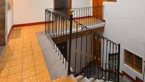 A staircase with a metal railing leading to a landing with a skylight above. - Hotel Mesón Cuévano (Guanajuato)