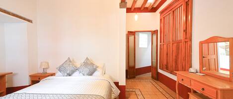Un dormitorio con cama, mesitas de noche, cómoda y espejo.