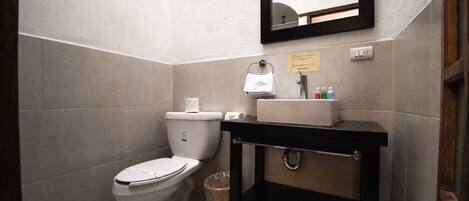 A small bathroom with a toilet, sink, and mirror.