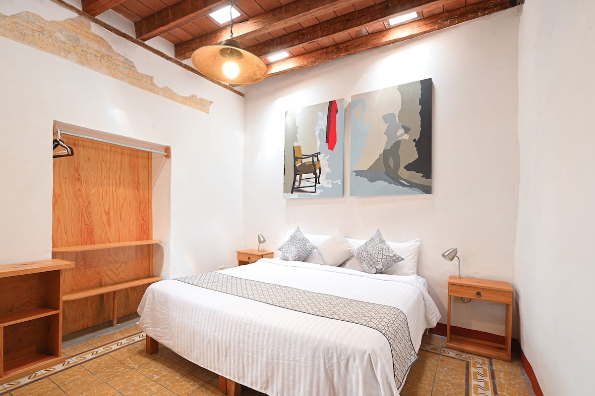 Une chambre à coucher avec un lit, des étagères en bois, une armoire et des œuvres d’art accrochées au mur.