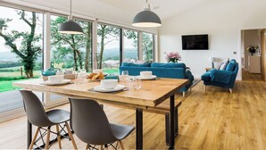 Un soggiorno moderno con zona pranzo, ampie finestre e vista sull'esterno.