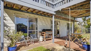 A covered patio area with outdoor seating, a barbecue grill, and a gas cylinder. - Dolphin Dreaming - 16 Dolphin Avenue (CARRICKALINGA)