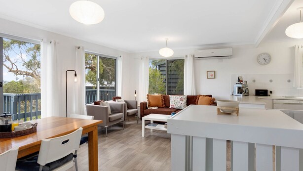 Eine moderne Küche mit Essbereich, ein Wohnzimmer mit Sofas und ein Balkon mit Blick.