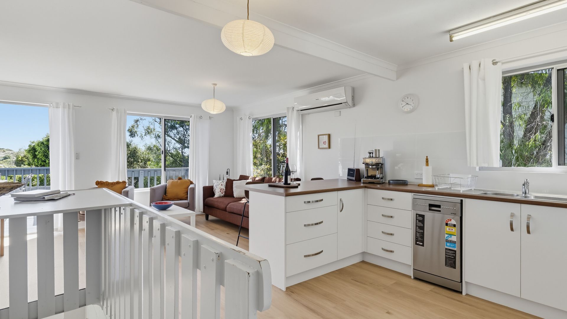 A modern kitchen with white cabinetry, a wooden countertop, and a built-in dishwasher.