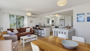 A modern living space with a kitchen, dining area, and seating. - Dolphin Dreaming - 16 Dolphin Avenue (CARRICKALINGA)